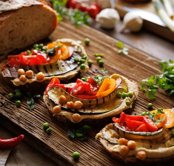 Vegetarian sandwiches with hummus and various vegetables on a wooden board, focus on the sandwich inside, close-up view