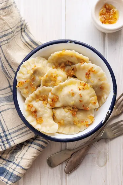 stock image Homemade dumplings with the addition of fried chopped onion in a bowl on a wooden table, top view. Traditional food