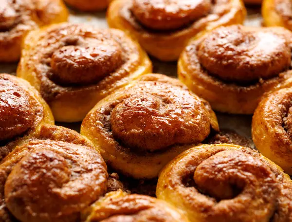 Traditional sweet spiral cinnamon buns kanelbullar, close up view. Cinnamon sweet buns on a rustic wooden background, close up view