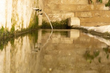 Castellote, Teruel, Aragon, İspanya, Maestrazgo kentindeki bir çeşmeden temiz ve kristal su çıkıyor. Sudaki güzel yansımalar, yalak görevi görüyor.