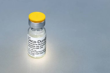 İspanya, Madrid, 01-13-2022, enjekte edilecek sıvı madde şişesi, gri arka planda nandrolon dekanoat adı verilen anabolik steroid.