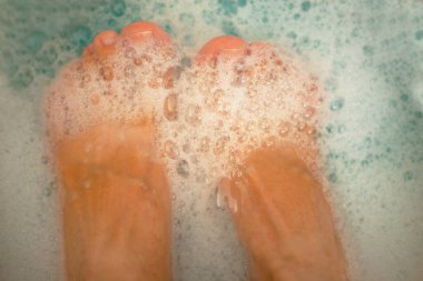 Mavi suyla kaplı köpüklü bacaklar. Köpüklü mavi su