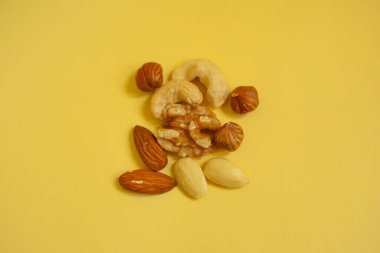 Sarı arka planda bir avuç karışık fındık