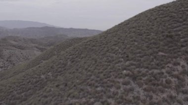 İspanya 'nın güneyindeki Almerya' da Tabernas Çölü, vadileri olan yarı kurak bir dağlık bölge, çalılar var, gökyüzü bulutlu.