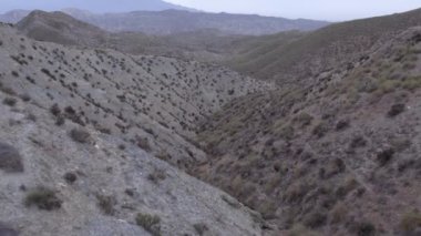 İspanya 'nın güneyindeki Almerya' da Tabernas Çölü, vadileri olan yarı kurak bir dağlık bölge, çalılar var, gökyüzü bulutlu.