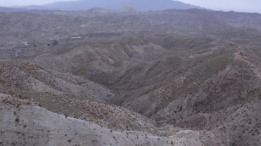 İspanya 'nın güneyindeki Almerya' da Tabernas Çölü, vadileri olan yarı kurak bir dağlık bölge, çalılar var, gökyüzü bulutlu.