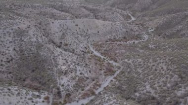 İspanya 'nın güneyindeki Almerya' da Tabernas Çölü, vadileri olan yarı kurak bir dağlık bölge, çalılar var, gökyüzü bulutlu.