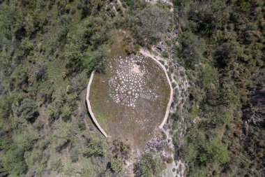 Mısır gevreğini eritmek için kullanılan dairesel yapı, yapı taştan yapılmış, ağaçlar ve çalılar var.