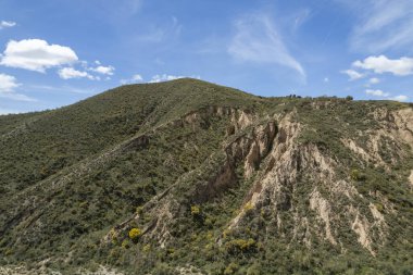 Granada 'nın güneyindeki bir dağın yamacında, yamaçta çalılar var, gökyüzünde çok az bulut var.