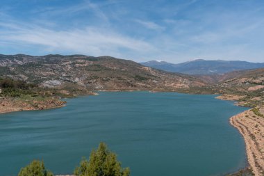 Güney İspanya 'da Beninar rezervuarı var, ağaçlar ve çalılar var, dağlık bir bölge, gökyüzünde bulutlar var.