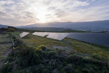 Granada 'nın güneyindeki fotovoltaik panel bitkisi, bitki örtüsü ve dağlık bir alan, gökyüzünde çok az bulut var.