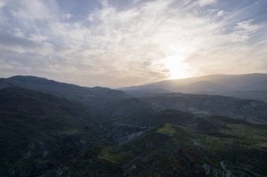 Granada 'nın (İspanya) güneyindeki dağlık arazide çalılar ve ağaçlar var, gökyüzünde bulutlar var.