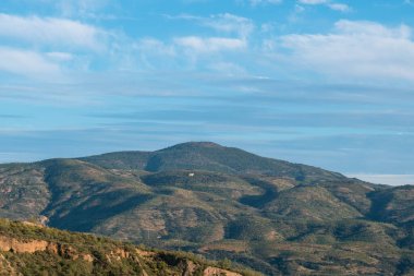 Granada 'nın güneyinde gün batımında dağ ormanları, çalılar, gökyüzünde bulutlar var.