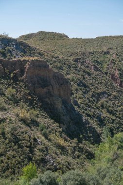 Granada 'nın güneyindeki dağlık arazi, çalıların ve ağaçların bitki örtüsü, arazi dik, gökyüzü temiz.