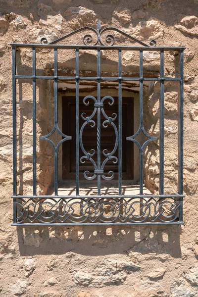 stock image metal grate on a window, the grate has ornamental drawings, the grate is black, the wall is made of stone and cement