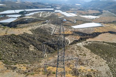 Granada dağında yüksek gerilim kolonu var, birkaç vadi var, seralar var, dağlarda ağaçlar var.