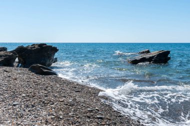 Akdeniz 'in sularındaki kayalar, su mavi ve gökyüzü berrak.