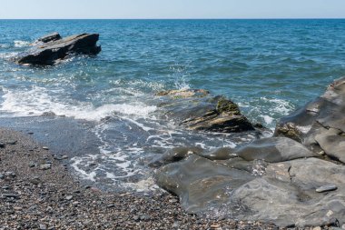 Akdeniz 'in sularındaki kayalar, su mavi ve gökyüzü berrak.