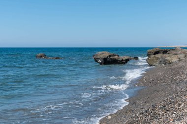 Akdeniz 'in sularındaki kayalar, su mavi ve gökyüzü berrak.