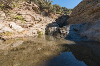 Güney Sierra Nevada geçidi, vadiden sular akıyor, ağaçlar ve çalılar var, sarp ve kayalık bir bölge.