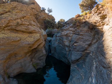Güney Sierra Nevada geçidi, vadiden sular akıyor, ağaçlar ve çalılar var, sarp ve kayalık bir bölge.