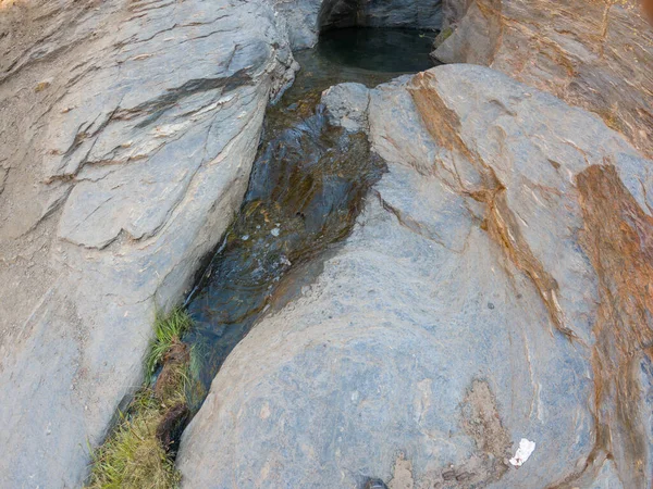 水从岩石中流下来 岩石与水的通道有裂缝 有青草 — 图库照片