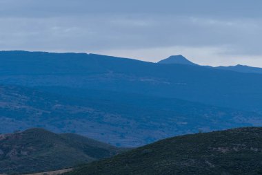 Granada 'nın güneyinde şafak vakti, bir dağ bölgesi, dağda bitki örtüsü var, gökyüzü bulutlu.