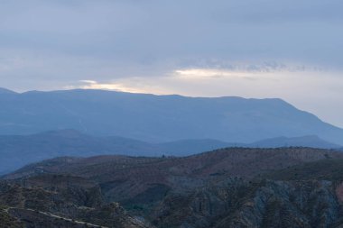 Granada 'nın güneyinde şafak vakti, bir dağ bölgesi, dağda bitki örtüsü var, gökyüzü bulutlu.