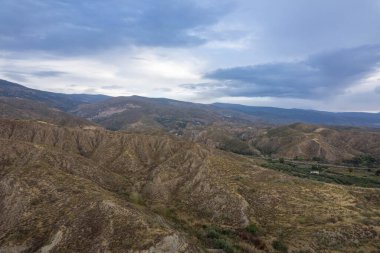 Granada 'nın güneyinde şafak vakti, bir dağ bölgesi, dağda bitki örtüsü var, gökyüzü bulutlu.