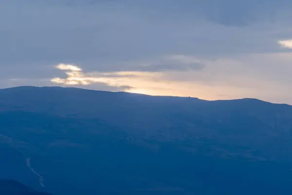 Granada 'nın güneyinde şafak vakti, bir dağ bölgesi, dağda bitki örtüsü var, gökyüzü bulutlu.