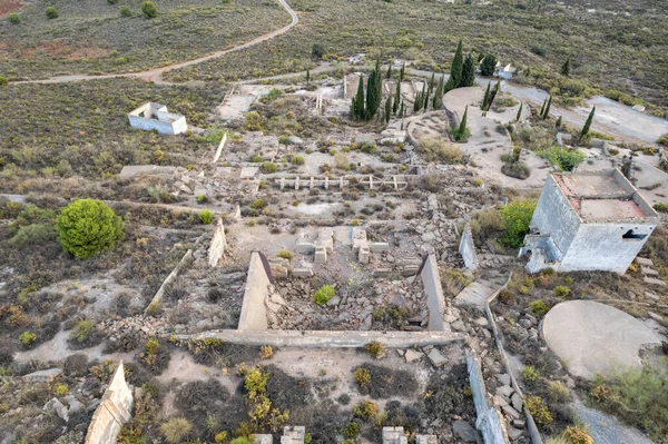 İspanya 'nın güneyinde eski bir maden fabrikasının kalıntıları, birkaç bina var, bir dağ bölgesi, çalılar ve ağaçlar var.