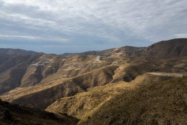 İspanya 'nın güneyindeki dağlık arazi, dağın yamaçlarında vadiler var, dağlar çalılarla kaplı, gökyüzü bulutlu.