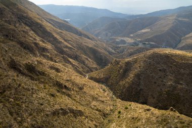 İspanya 'nın güneyindeki dağlık arazi, dağın yamaçlarında vadiler var, dağlar çalılarla kaplı, gökyüzü bulutlu.