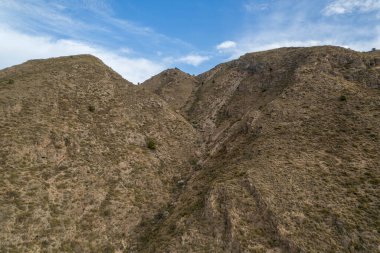 İspanya 'nın güneyindeki dağlık arazi, dağın yamaçlarında vadiler var, dağlar çalılarla kaplı, gökyüzü bulutlu.