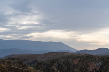 İspanya 'nın güneyindeki Granada dağları, dağların birkaç vadisi var, çalıların ve ağaçların bitkileri var, gökyüzü bulutlu.