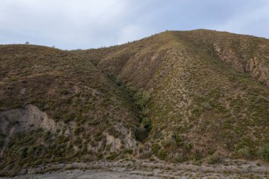 İspanya 'nın güneyindeki Granada dağları, dağların birkaç vadisi var, çalıların ve ağaçların bitkileri var, gökyüzü bulutlu.