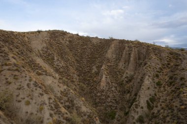 İspanya 'nın güneyinde sarp arazi, çalılı birkaç vadi var, yarı kurak bir arazi, gökyüzünde bulutlar var.