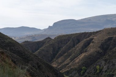 İspanya 'nın güneyindeki Granada dağları, dağların birkaç vadisi var, çalıların ve ağaçların bitkileri var, gökyüzü bulutlu.
