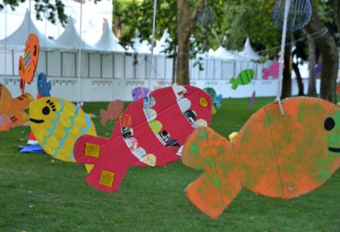 Pembe boyalı karton balıklar oyun sahasında ipte sallanıyor.