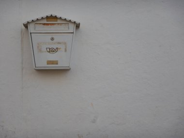 Arka planda beyaz bir duvarda asılı duran eski beyaz posta kutusu