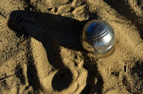 一个单独的布尔斯金属球在沙滩上 下午晚霞的阴影很长 — 图库照片
