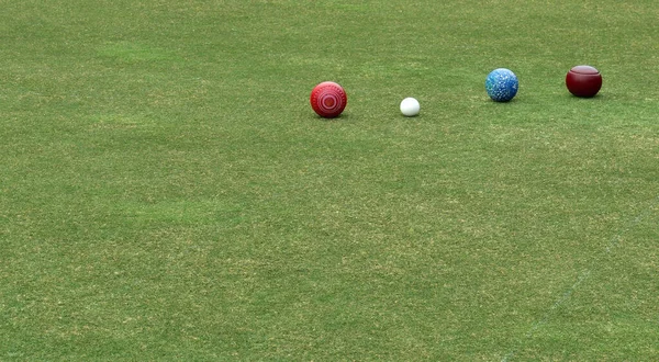 Some colored lawn bowls in a line with the white ball known as the jack