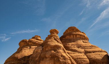 Mavi gökyüzü ve Hegra 'da El Ula Suudi Arabistan yakınlarındaki bulutlara karşı yuvarlak koni şekilli monolitler