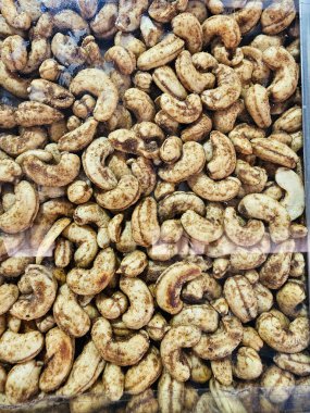 Kavrulmuş kaju fıstığının yakın plan görüntüsü tuzlu, yoğun bir bardakta sergilenmiş, doğal formlarını ve dokusunu ön plana çıkarıyor..