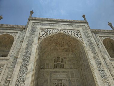 Bu Tac Mahal 'in ana kemerlerinden birine daha yakın bir görüntü. Arap kaligrafisi ve çiçek motiflerinin yer aldığı siyah mermer işlemeler, cilalanmış beyaz mermer yüzeyde göze çarpıyor. Kaliteli karviyi de görebilirsiniz.