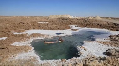 Güzel genç bir kadın Mısır 'ın Siwa Oasis kentindeki Salt Plains ve Lakes' de yüzüyor.