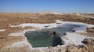 Güzel genç bir kadın Mısır 'ın Siwa Oasis kentindeki Salt Plains ve Lakes' de yüzüyor.