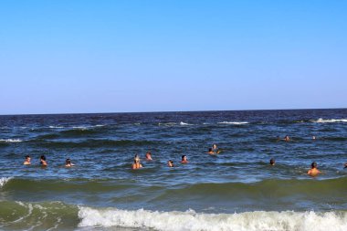 Dalgalar, deniz ve Yüzücüler Açık Mavi Gökyüzü Altında