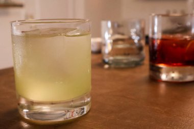 Close-Up of Three Assorted Cocktails on a Wooden Table in a Cozy Bar Setting clipart