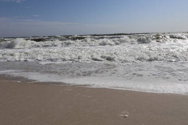 Karadeniz 'in dalgaları kumlu kıyıya çarpar ve berrak mavi gökyüzünün altında canlı, köpüklü bir sörf yaratır. Sahne, doğanın kıyı dinamiklerinin enerjisini ve güzelliğini yakalıyor..